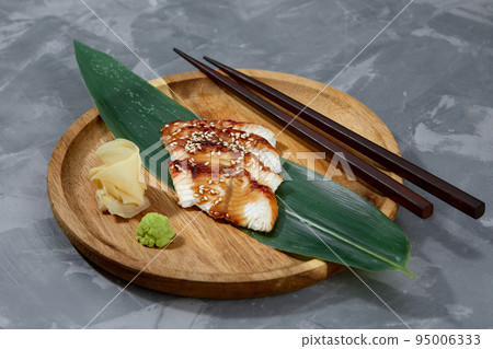 Fresh seafood sashimi smoked eel on slate board with wasabi and ginger on black background 95006333