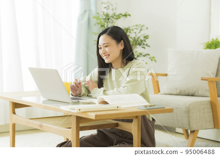 Young female college student high school student studying while looking at a computer 95006488