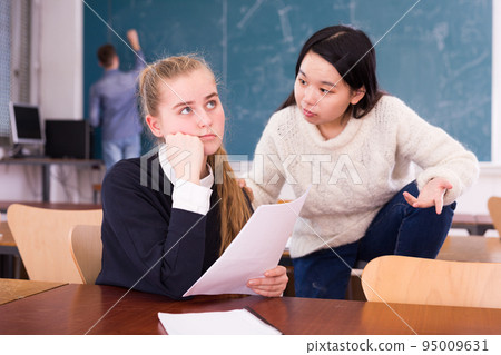 Girls university students sitting at desk and preparing for exams 95009631