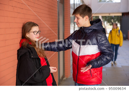 Teenage girl and boy schoolmates talking outdoor Teenage girl and boy schoolmates talking outdoor 95009634