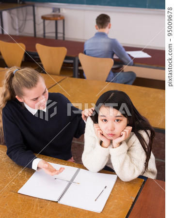 Female university students sitting at desk preparing for exams 95009678