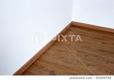 Laminate wood floor with blank white wall 95009794