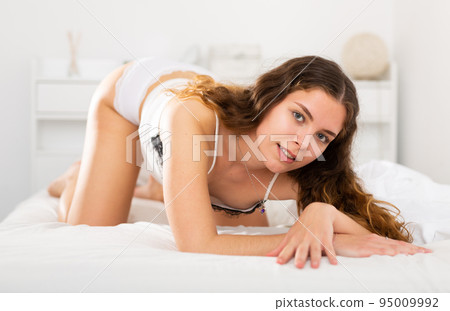 Girl with brown wavy hair in lace underwear lying on bed 95009992