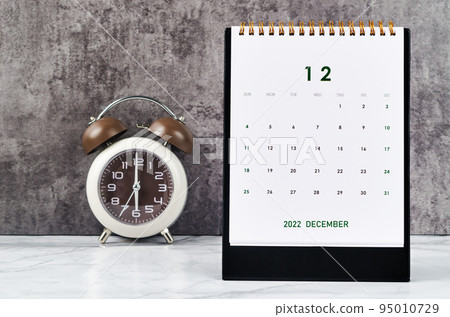 The December 2022 Monthly desk calendar for 2022 year and Alarm clock vintage background. 95010729