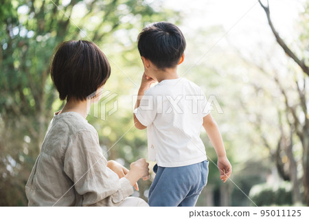 Rear view of parent and child playing in the park 95011125