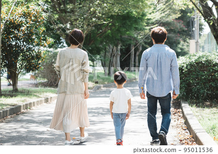 Parents and children walking on the sidewalk in the park 95011536