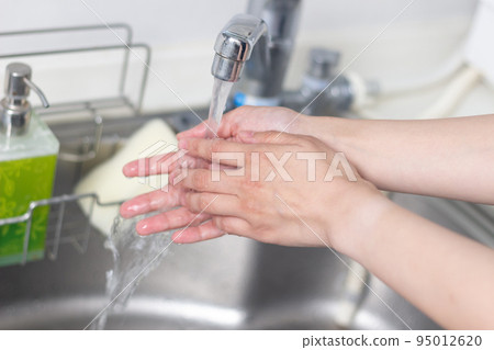 Hands of a woman washing her hands in the kitchen sink Hands of a woman washing her hands in the kitchen sink 95012620