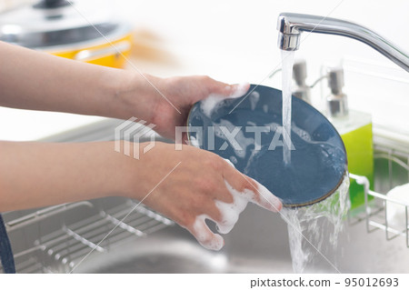 Hands of a woman washing dishes Hands of a woman washing dishes 95012693