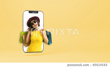 Beautiful young Asian woman carrying colorful bags shopping online with mobile phone on yellow background Beautiful young Asian woman carrying colorful bags shopping online with mobile phone on yellow background 95014583