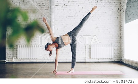 Attractice young woman advanced yoga student is doing combination of balancing and power asanas in modern wellness center. Yoga for health, beautiful body and relaxation concept. 95014722