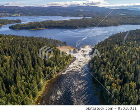Aerial view famous waterfall Tannforsen northern Sweden, with a rainbow in the mist and rapid flowing cascades of water 95016011
