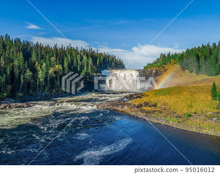 Aerial view famous waterfall Tannforsen northern Sweden, with a rainbow in the mist and rapid flowing cascades of water Aerial view famous waterfall Tannforsen northern Sweden, with a rainbow in the mist and rapid flowing cascades of water 95016012