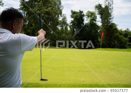 man white shirt blue pants In his hand, the putter prepares for the next golf shot. Sports that people around the world play during quarantine for health. man white shirt blue pants In his hand, the putter prepares for the next golf shot. Sports that people around the world play during quarantine for health. 95017377