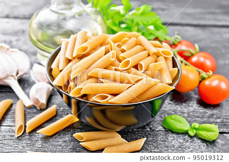 Penne whole grain in bowl with vegetables on board 95019312