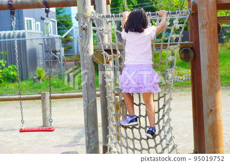 Back view of girl playing on athletic playground equipment in park Back view of girl playing on athletic playground equipment in park 95019752