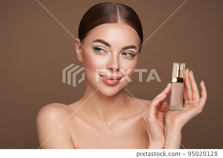 Portrait beautiful young woman with foundation bottle Portrait beautiful young woman with foundation bottle 95020128