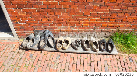 Vintage wooden shoes in front of a brick wall in the Netherlands Vintage wooden shoes in front of a brick wall in the Netherlands 95020236