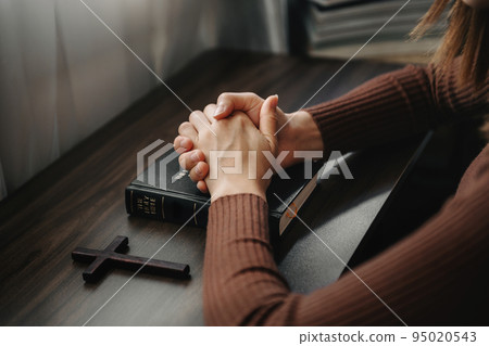 Hands together in prayer to God along with the bible In the Christian concept and religion, woman pray in the Bible on the table.. Hands together in prayer to God along with the bible In the Christian concept and religion, woman pray in the Bible on the table.. 95020543