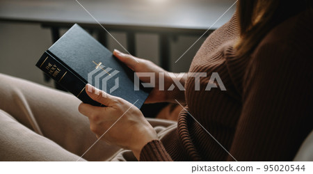 Woman sitting and praying holding a Holy Bible pray to God. Woman sitting and praying holding a Holy Bible pray to God. 95020544