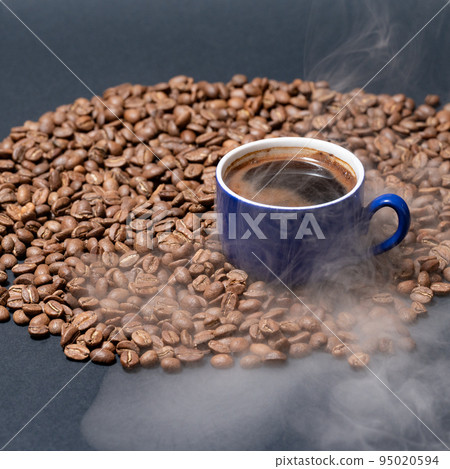 A cup of coffee and coffee beans on a black background, an aromatic and energy drink. A cup of coffee and coffee beans on a black background, an aromatic and energy drink. 95020594