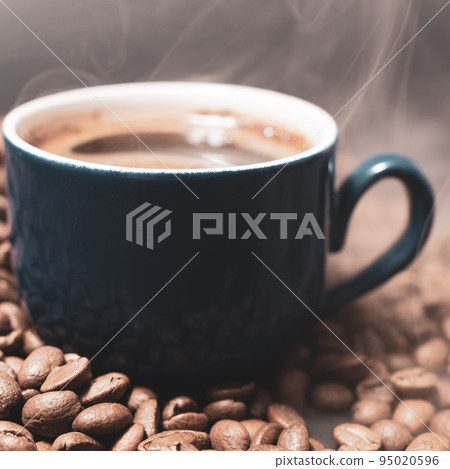 A cup of coffee with beans scattered nearby A cup of coffee with beans scattered nearby 95020596