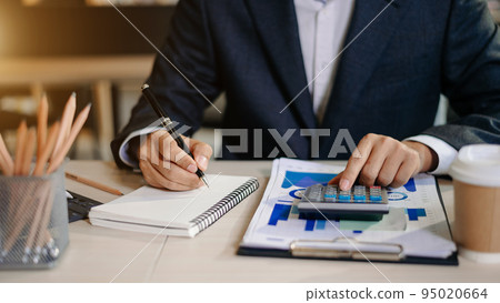 businessman working on desk office with using a calculator to calculate the numbers, finance accounting concept. 95020664