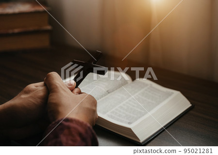 Close up of an open bible with a cross for morning devotion on a wooden table with window lights. Close up of an open bible with a cross for morning devotion on a wooden table with window lights. 95021281