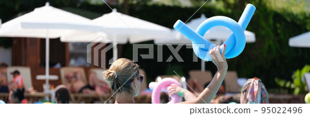 Female instructor holding blue noodle at sports workout in swimming pool 95022496