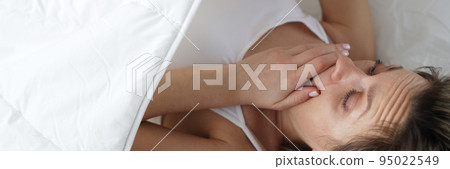 Young woman looking under covers and wondering 95022549