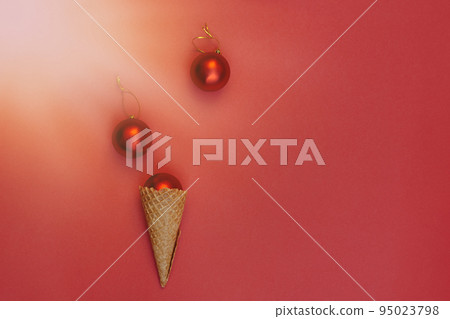 Soft selective focus Christmas balls decoration in waffle cone on red background under bright sun rays. Round toys with gold thread. Flat Lay Soft selective focus Christmas balls decoration in waffle cone on red background under bright sun rays. Round toys with gold thread. Flat Lay 95023798