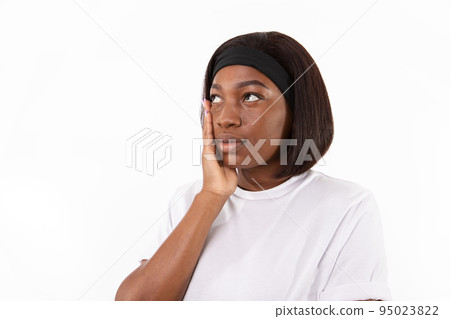 Portrait of upset young woman touching her face 95023822
