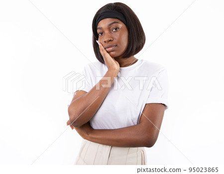 Portrait of confident young woman standing with hand on cheek Portrait of confident young woman standing with hand on cheek 95023865