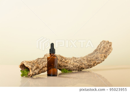 Trendy composition of Blank amber glass essential oil bottle, dried branch and moss on beige background. Product, cosmetic, perfume, jewellery mock up 95023955