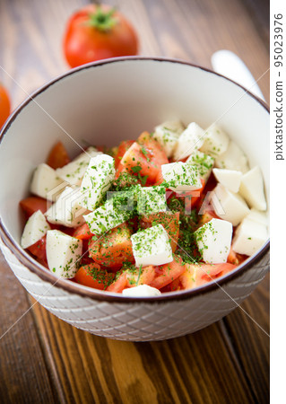 salad of fresh ripe tomatoes with mozzarella and spices in a bowl 95023976