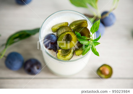 sweet homemade yogurt with fresh plum slices in a glass 95023984