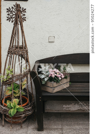 Vintage Outdoor Furniture, Mums And Nik-naks. Wooden Bench In Front Garden With Flower Boxes. Box With Flowers On The Bench. Wooden Bench In Front Garden With Flower Boxes. Box With Flowers On The Vintage Outdoor Furniture, Mums And Nik-naks. Wooden Bench In Front Garden With Flower Boxes. Box With Flowers On The Bench. Wooden Bench In Front Garden With Flower Boxes. Box With Flowers On The 95024277