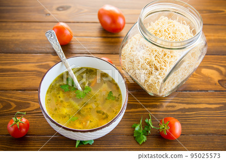 Chicken noodle soup with parsley and vegetables in a white plate Chicken noodle soup with parsley and vegetables in a white plate 95025573