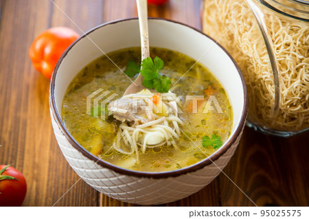 Chicken noodle soup with parsley and vegetables in a white plate 95025575