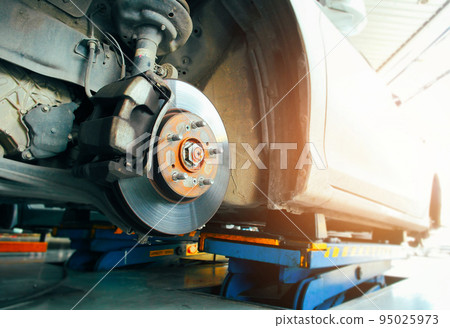 Front disc brakes and calipers that remove the wheels of a car in the auto repair garage 95025973
