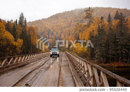 SUV on the wooden bridge over a mountain river 95026440