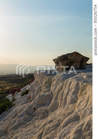 Flowers blooming on the white stalactites of Pamukkale, Hierapolis, Turkey and a hut built on a lime ledge 95026754
