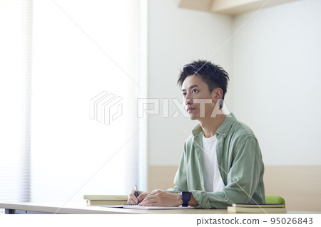 A young Japanese male student studying independently using textbooks. A young Japanese male student studying independently using textbooks. 95026843