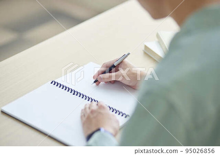 A young male university student concentrating on studying for an exam in a cram school classroom. A young male university student concentrating on studying for an exam in a cram school classroom. 95026856