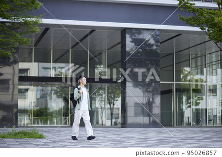 A young male student with a backpack on walking down a university corridor. A young male student with a backpack on walking down a university corridor. 95026857