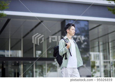 A young Japanese man standing inside a campus building. A young Japanese man standing inside a campus building. 95026859