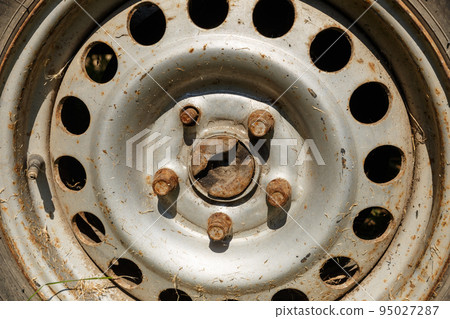 old rusty wheel in the sunlight. wheel rim, bolts and capped schrader valve. Close-up old rusty wheel in the sunlight. wheel rim, bolts and capped schrader valve. Close-up 95027287