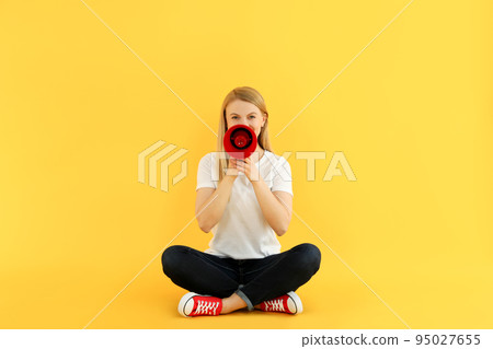 Young woman with megaphone on yellow background Young woman with megaphone on yellow background 95027655