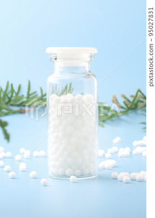Homeopathic globules and glass bottle near with fresh juniper branches close-up on blue background. Alternative Homeopathy medicine herbs.Vertical. Copy space. 95027831
