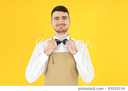 Concept of occupation, young waiter on yellow background 95028134