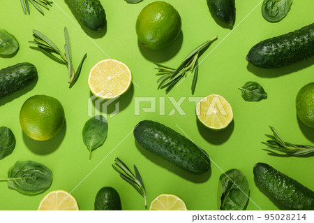 Flat lay with cucumbers, limes, basil and rosemary on green background Flat lay with cucumbers, limes, basil and rosemary on green background 95028214